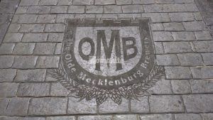 View of OMB logo in decorative concrete at Olde Mecklenburg Brewery in Charlotte, NC, using Bomanite Imprint Systems featuring the Running Bond Belgian Block pattern installed by Carolina Bomanite.